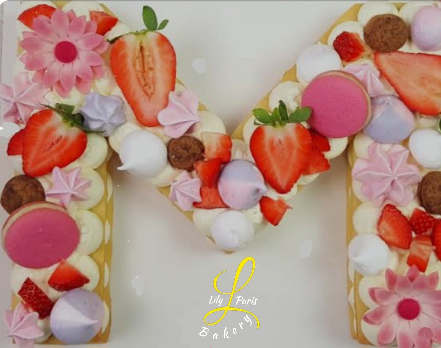 Letter M cake with strawberries and macarons